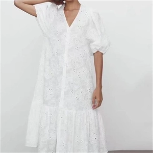 Gros plan sur la broderie anglaise délicate et l'ourlet à volants de la robe blanche