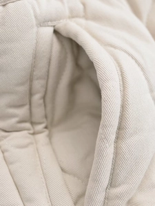 Macro shot of twill cotton fabric texture and stitching on an oatmeal puffer vest