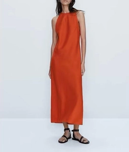 Détail du tissu d'une robe midi orange sans manches en satin avec un lustre doux