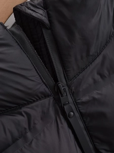 Detailed macro view of black quilted jacket featuring a metal zipper and buckle accent