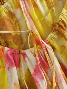 Dettaglio del tessuto tie-dye colorato e dei lacci a girocollo su un mini abito estivo