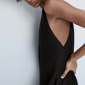 Détail de la coupe sans manches et du tissu fluide noir sur une robe longue d'été Y2K