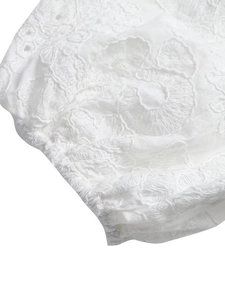 Robe blanche brodée avec motifs floraux ajourés et détails de volants smockés