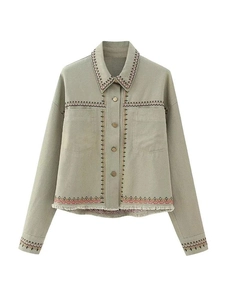Detail of bohemian embroidery and frayed fringe hem on a light green utility jacket