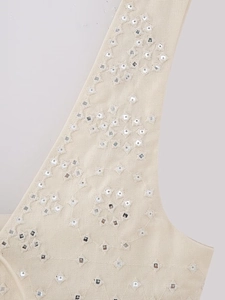Macro detail of bohemian cream vest featuring ethnic embroidery and small mirror sequins