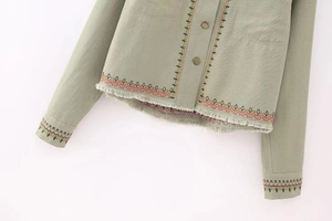 Detail of green cotton jacket with ethnic embroidery, frayed edges and bronze buttons