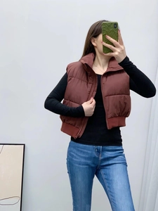 Detailed view of women's brown quilted vest with stand collar and elastic ribbed hemline