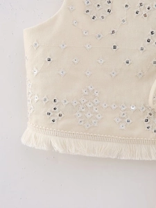 Detail of bohemian cream vest featuring shisha embroidery mirrors and fringe trim