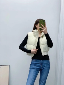Detail of cream white cropped puffer vest with horizontal quilting and stand collar