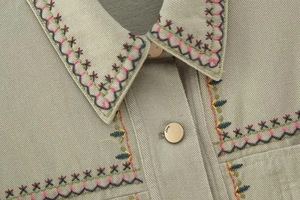 Close-up of colorful wave and star embroidery on a vintage denim jacket collar