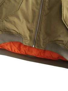 Close-up of olive green bomber jacket with orange quilted lining and ribbed hem