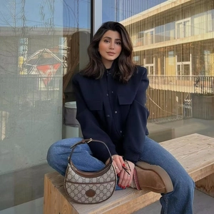 Close-up detail of a navy blue bomber jacket styled with a GG Supreme canvas handbag