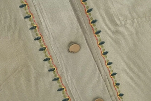 Detail of Y2K style corduroy jacket with colorful leaf embroidery and metal buttons