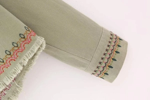 Detail of colorful ethnic embroidery and tassel trim on khaki twill jacket sleeve