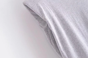 Detailed macro view of light grey knitted fabric texture and precise stitching on a T-shirt