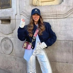 Cropped bomber jacket with stand collar and metallic silver trousers on street background