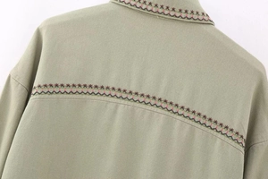 Detail of Y2K style sage green jacket featuring exquisite star embroidery and twill texture
