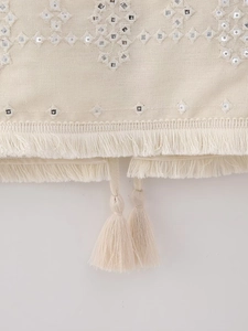 Detail of bohemian embroidery with mirror sequins and tassel fringe on a cream vest