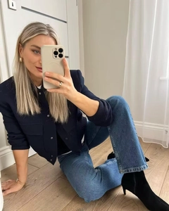 Detail of navy pilot jacket with ribbed trim paired with blue jeans and black boots
