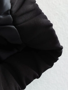 Detailed macro view of black y2k bomber jacket elastic cuff with durable woven texture