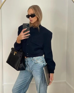 Detail of dark blue cropped bomber jacket with high collar and large front flap pockets