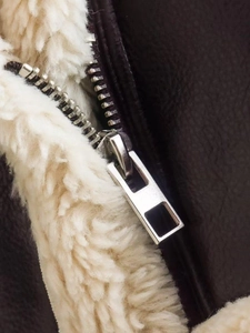 Close-up of brown leather jacket with white faux shearling lining and silver metal zipper