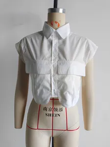 Detail of white cropped sleeveless shirt featuring lapel collar and chest flap pockets