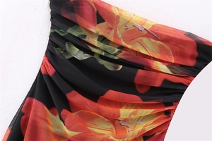 Detail of ruched mesh fabric with vibrant orange floral print on a black base dress