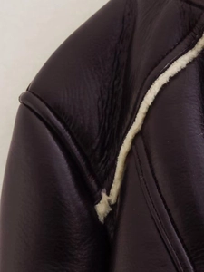 Detail of dark faux leather jacket showing plush faux shearling lining and contrast seams