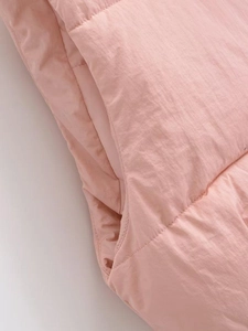Detailed close-up of pink quilted vest featuring horizontal stitching and side pocket