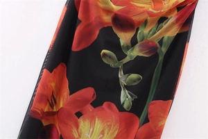 Close-up of lightweight black mesh fabric with orange lily floral print pattern