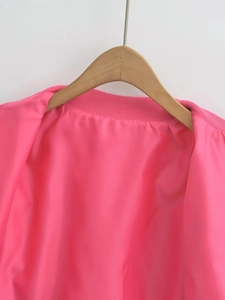 Detail of bright pink bomber jacket with smooth satin lining and ribbed collar stitching