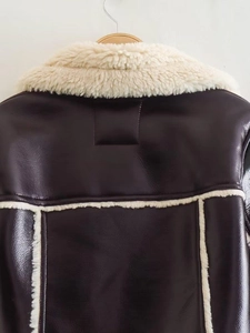 Detail of dark brown leather jacket with off-white fleece trim and grainy texture