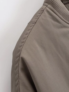 Detalle macro de chaqueta bomber taupe con cuello acanalado y costuras reforzadas