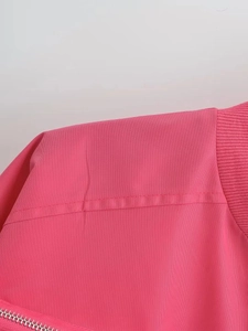 Close-up of pink Y2K bomber jacket fabric with ribbed collar and silver metal zipper
