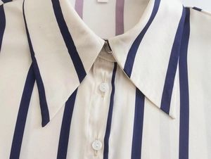 Detailed close-up of striped vertical patterns and white buttons on the shirt collar