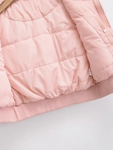 Detail of pink quilted vest lining with ribbed hem and woven laundry care label