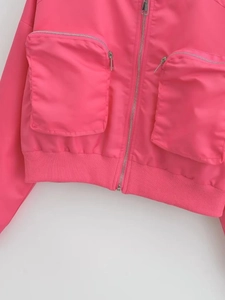 Detail of bright pink Y2K bomber jacket featuring utility pockets and ribbed hemline