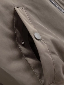 Detalle del bolsillo lateral con botón a presión mate en la tela de la chaqueta