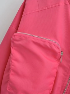 Detail of rose red Y2K bomber jacket featuring a 3D utility pocket with silver zipper