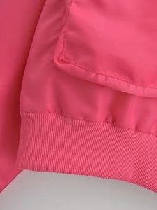 Macro detail of bright pink Y2K bomber jacket featuring ribbed cuffs and flap pocket design