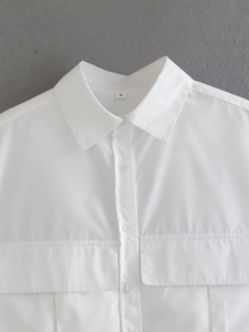 Detailed close-up of white cropped shirt collar with front buttons and utility pockets