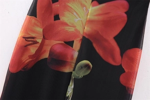 Detail of Y2K floral print on black mesh fabric with orange flowers and stitching