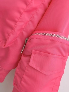 Detail of hot pink bomber jacket featuring metallic zipper pockets and ribbed cuffs