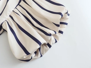 Detail of blue vertical stripes and elastic puff sleeve cuffs on beige fabric