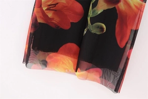 Close-up of translucent black mesh fabric with vibrant red and orange floral prints