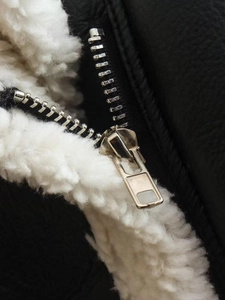 Detail of premium black leather jacket with soft white shearling lining and metal zipper