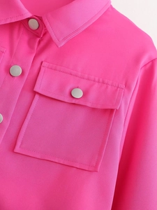 Gros plan sur la veste texturée rose rouge avec col à revers et boutons métalliques argentés