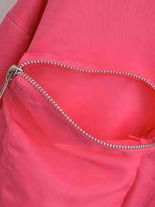 Macro detail of silver metal zipper on high-saturation pink y2k windbreaker fabric