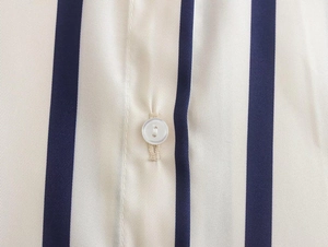 Close-up of blue vertical stripes on cream fabric with a white button detail